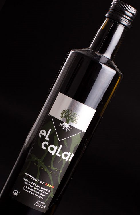 Botella de «el calar» virgen extra sobre fondo oscuro